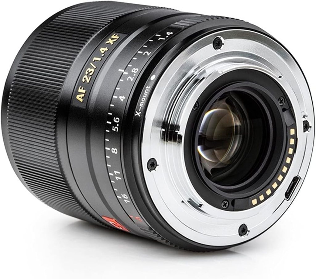 Close-up of a black camera lens with a silver mount, labelled AF 23/1.4 XF, showing aperture and focus markings.