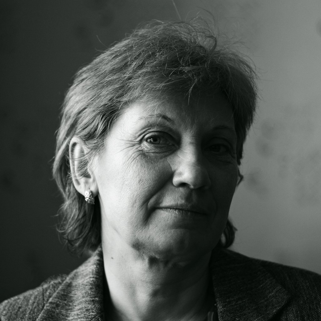 A black and white portrait of a woman with short hair, gently smiling and looking to the side, showcasing her facial features and expressions.