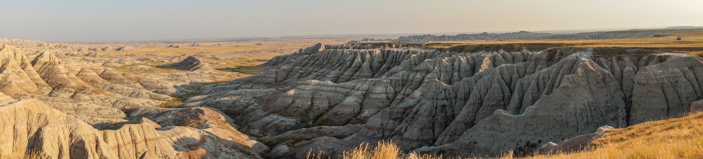 Panoramic view of the Badlands landscape featuring rugged cliffs and expansive plains under a clear sky.
