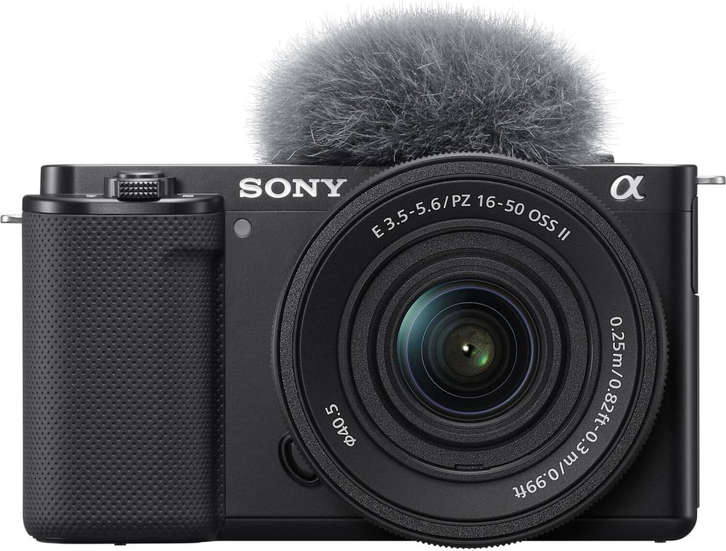 Front view of a Sony camera with a detachable lens and a fuzzy microphone windscreen attached.