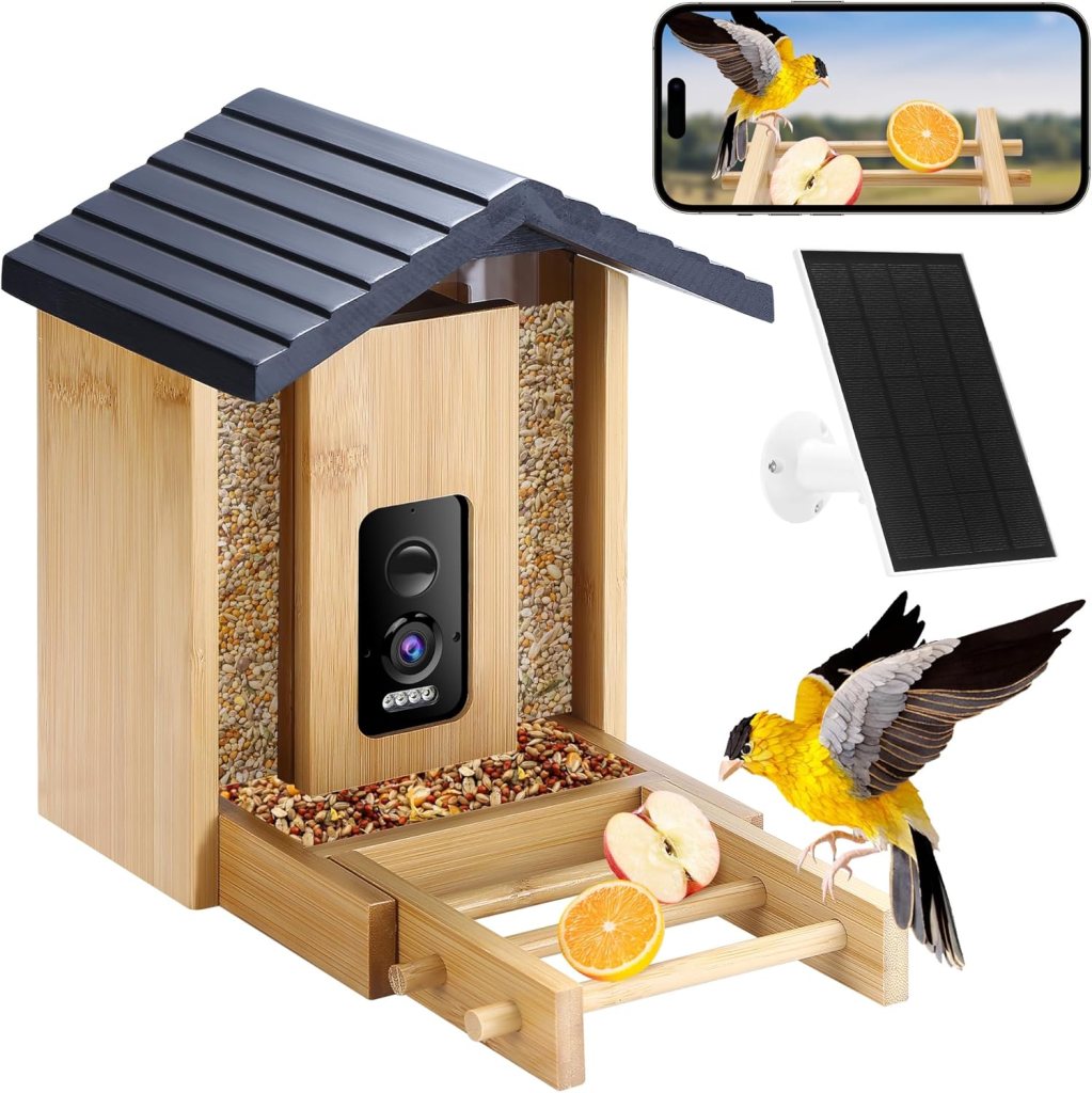 A bird feeder made of bamboo, featuring a slanted roof, filled with seeds and sliced fruits. An attached camera and solar panel are visible, alongside an image of a yellow bird perched on the feeder.