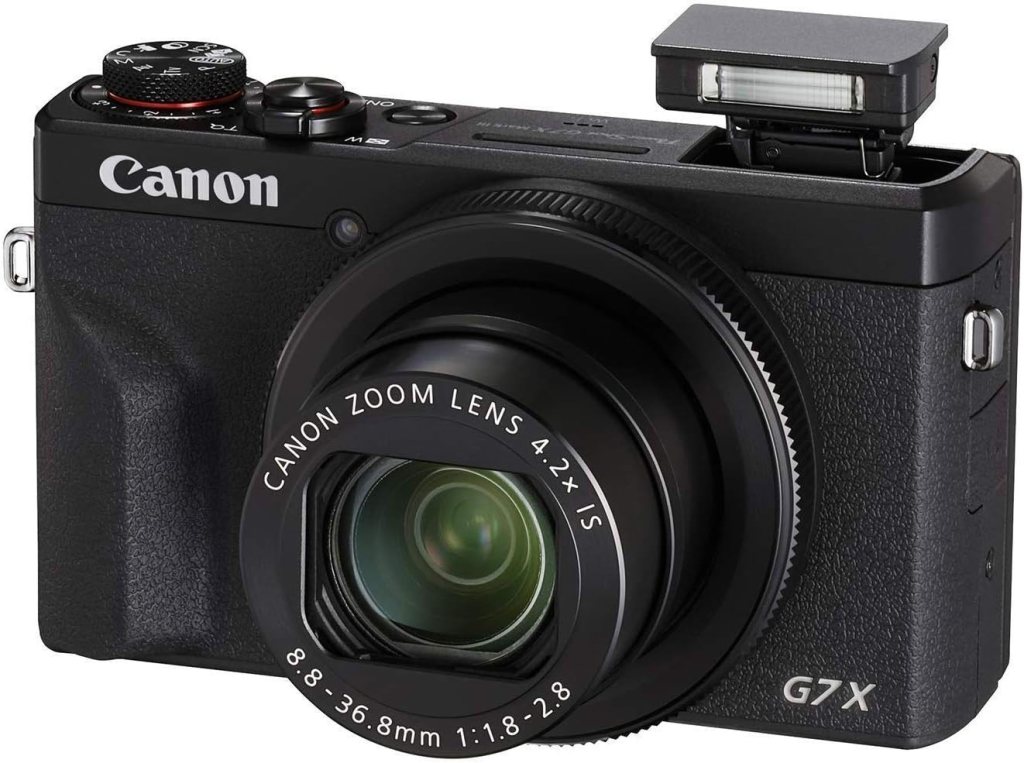 A black Canon G7X digital camera with a zoom lens and built-in flash.