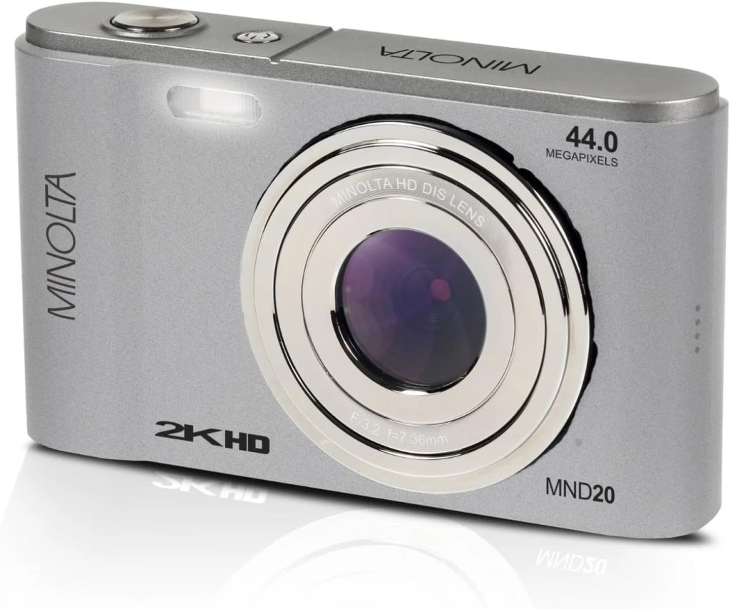 A silver Minolta digital camera with a 44.0 megapixel lens, showcasing a sleek design and the brand name prominently displayed.