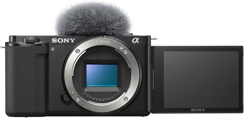 Front view of a Sony camera with a furry microphone and a flipped-out screen, showcasing its E-mount and image sensor.