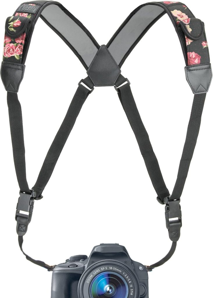 A floral-patterned camera harness with adjustable straps, designed to support and carry a DSLR camera.