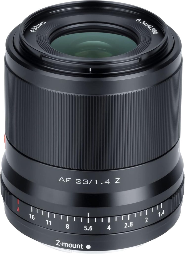 Close-up of a black camera lens with a 23mm focal length and f/1.4 aperture, featuring a Z-mount and depth of field markings.